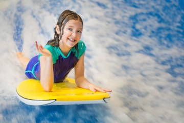 a young girl riding a wave on a surf board